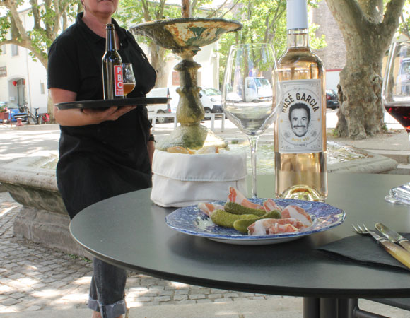 Femme tenant un plateau devant une table avec assiette de charcuterie & vin